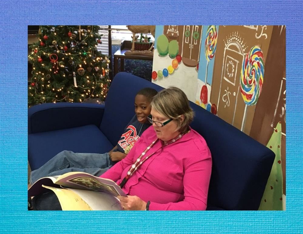 A teacher reads to a student in the media center.