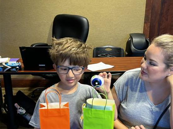 Little boy with two bags, sitting next to a woman